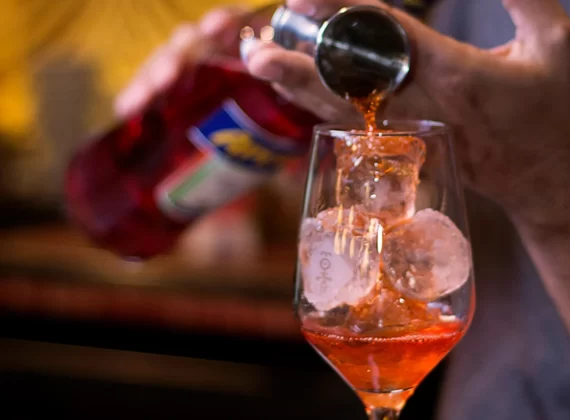 an Aperol cocktail being poured over ice in a cocktail glass